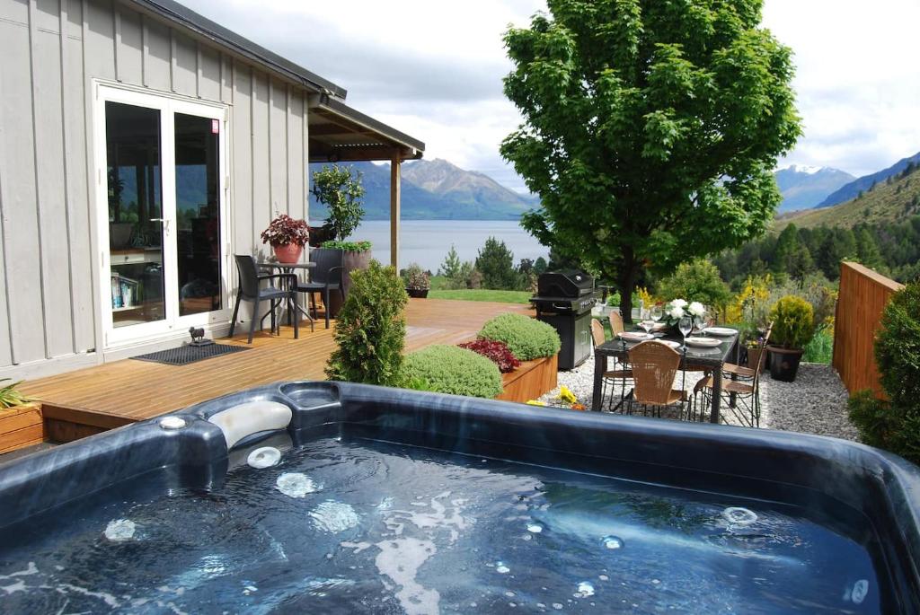 Closeburn的住宿－Private Cottage with Spa and Amazing Lake Views，房屋旁甲板上的热水浴池