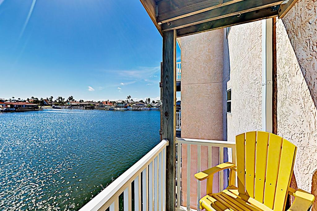 une chaise jaune assise sur une terrasse couverte à côté de l'eau dans l'établissement Fortuna Sea Brisas Condominiums #4, à Corpus Christi