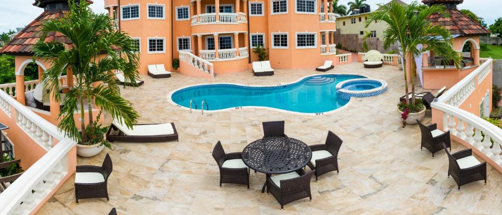 een patio met een zwembad en een tafel en stoelen bij Villa Sweet Villa - Montego Bay in Montego Bay