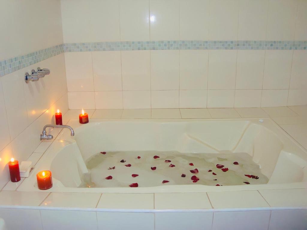 una bañera con dos velas y rosas. en Hotel Madrigal, en Portoviejo