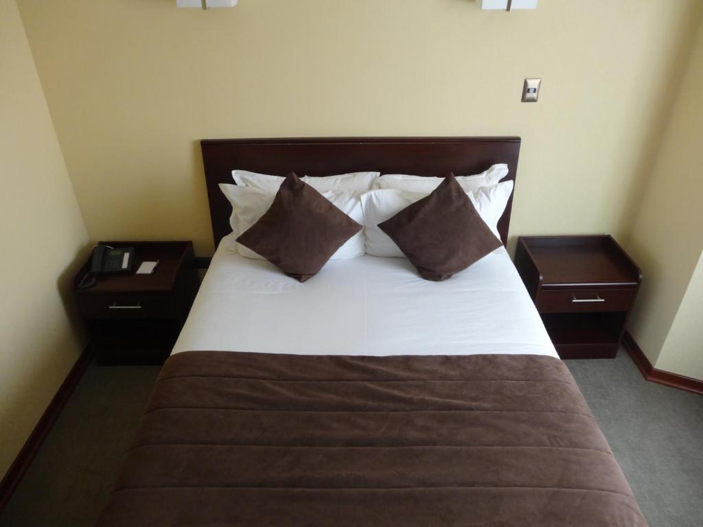 a bedroom with a bed with two night stands and two tables at Hotel Costa Pacifico - Express in Antofagasta