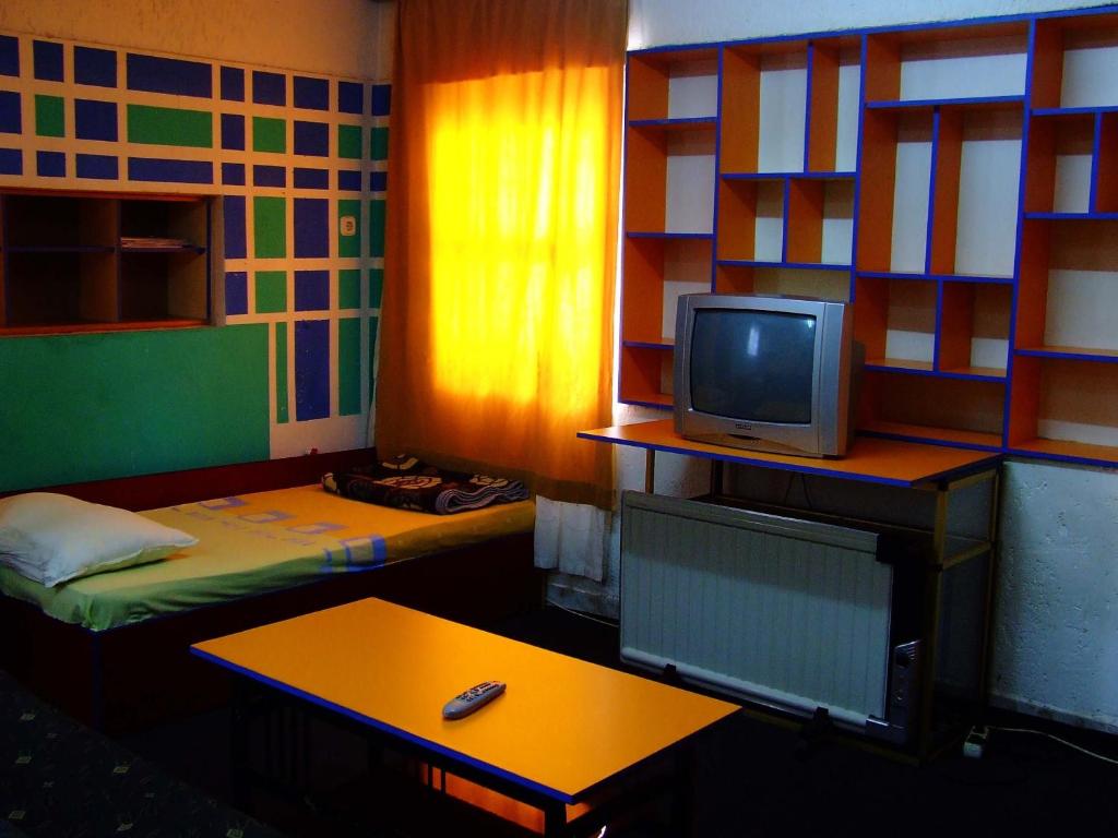 Habitación con 2 camas, TV y mesa. en Hostel Domestika, en Bitola