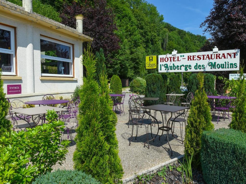 a restaurant with tables and chairs in a garden at Auberge des Moulins in Baume-les-Dames