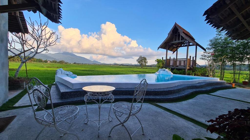 um pátio com uma mesa e cadeiras ao lado de uma piscina em Rumah Bendang Langkawi Villa Pool em Pantai Cenang