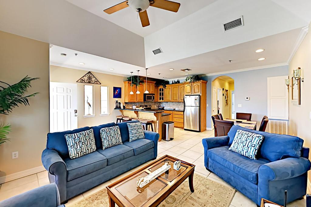 a living room with blue couches and a kitchen at Garden Breeze Condominiums #3 in South Padre Island