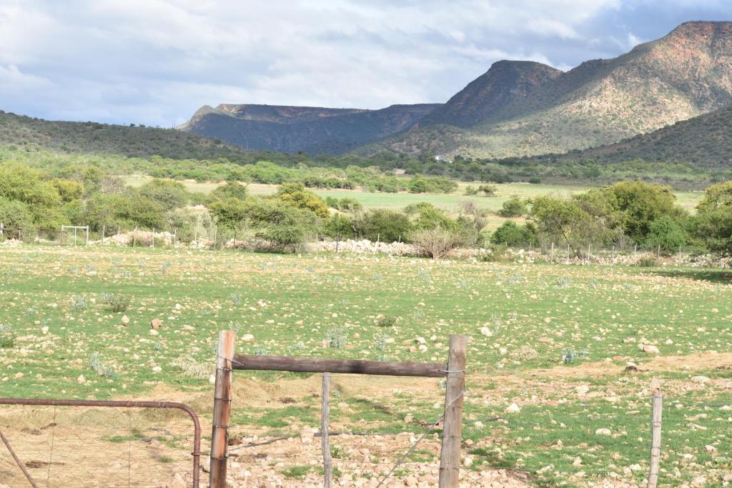 una valla en un campo con montañas en el fondo en Baviaanskloof Guest Cottages, en Studtis