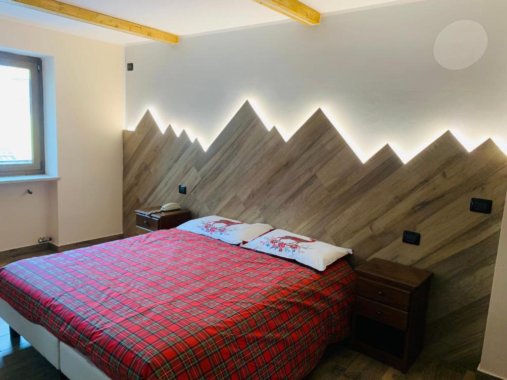 1 dormitorio con cama roja y cabecero de madera en Hotel Ristorante Ligure, en Vinadio