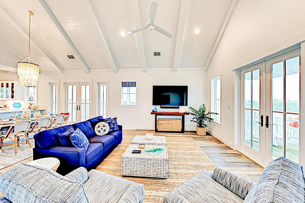 a living room with blue couches and a tv at Golf Course Living at Palmilla Beach in Port Aransas