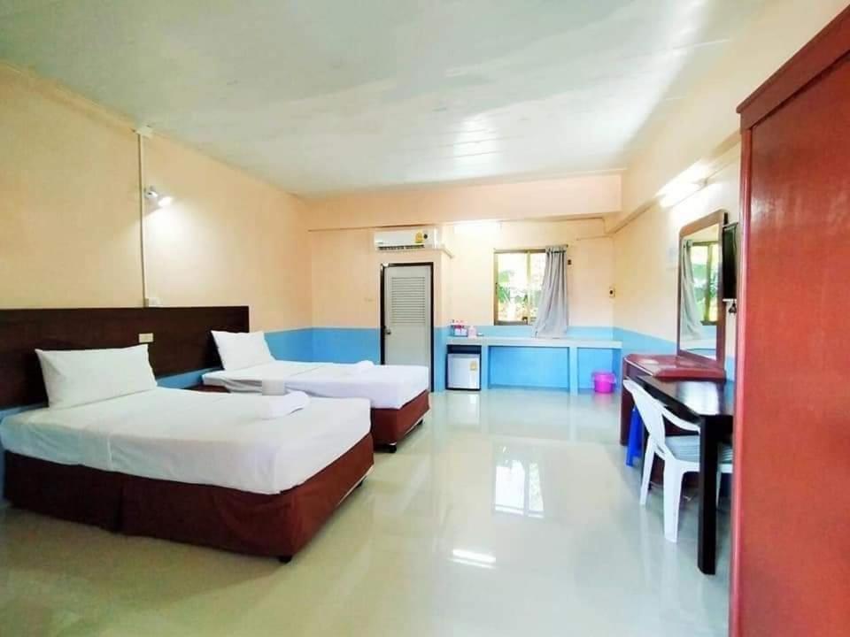 a bedroom with two beds and a desk in it at Station Hotel in Trang