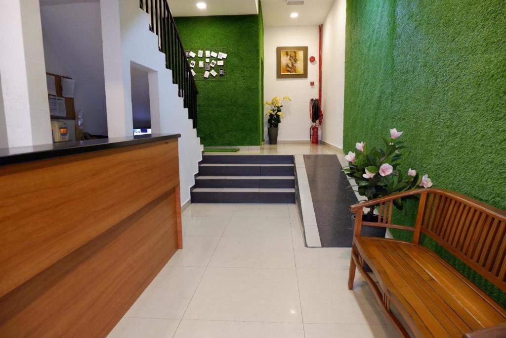 un vestíbulo con una pared verde, escaleras y bancos en Bintang Garden Hotel en Kuala Lumpur