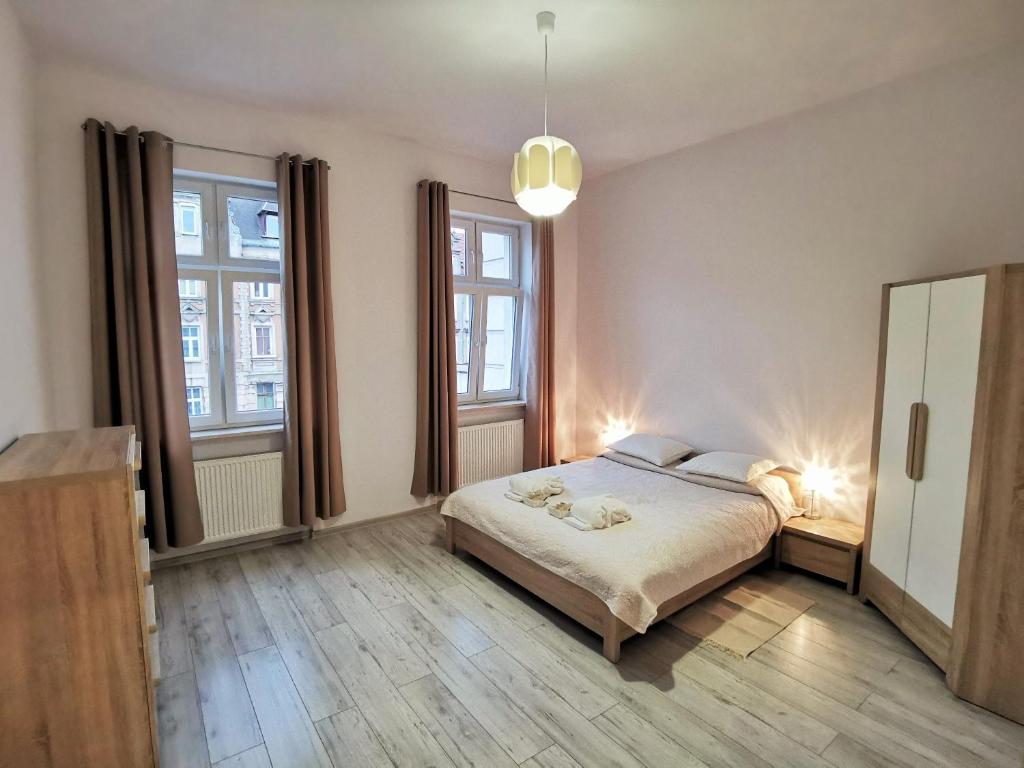 a bedroom with a bed and two windows at Apartament Seven in Legnica