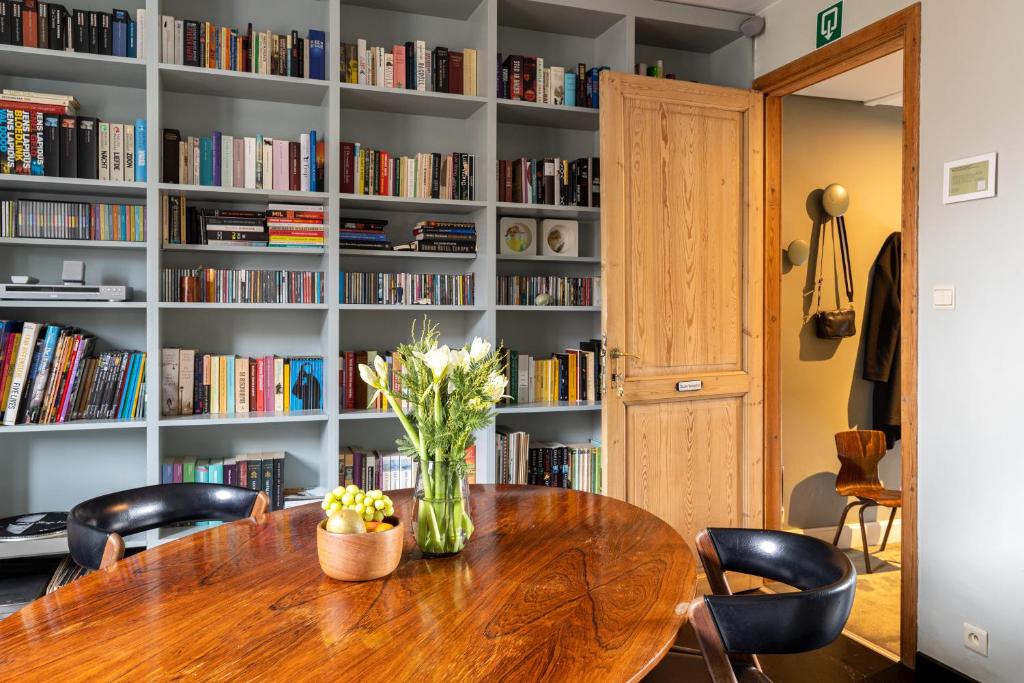 a dining room table with chairs and a book shelf with books at Studio Spiegelhof in Ghent