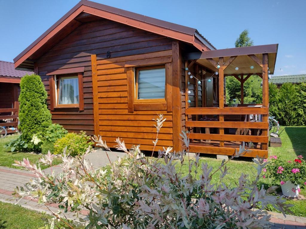 a wooden cabin with a porch in a garden at Zielony Gaj in Wicie