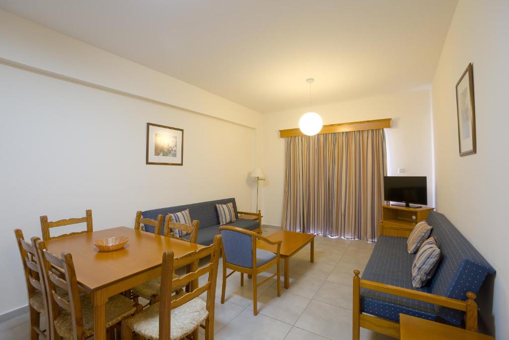 uma sala de estar com uma mesa e uma sala de jantar em Kefalos Damon Hotel Apartments em Pafos