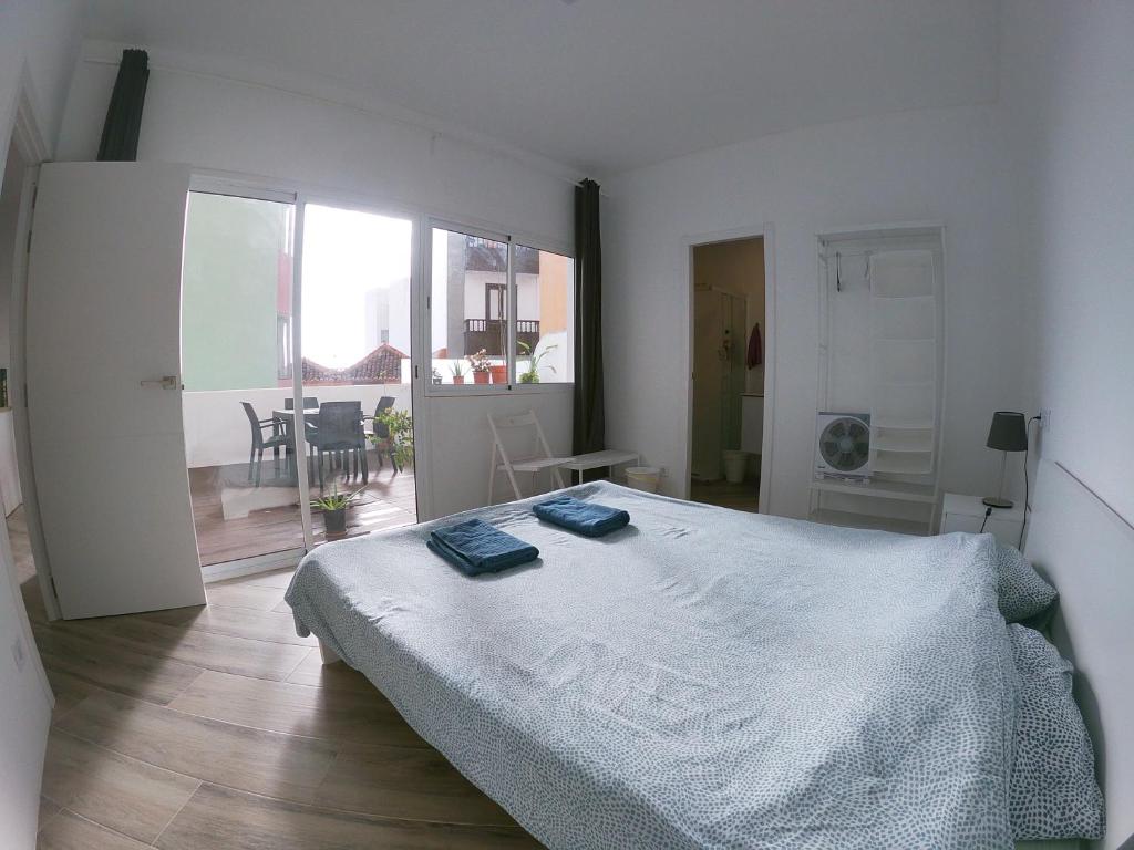 Dormitorio blanco con cama y ventana grande en Ático Moderno - Out of Blue, en Santa Cruz de la Palma