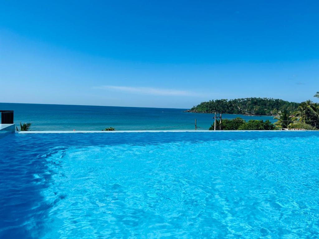 a swimming pool with the ocean in the background at One World Mirissa in Mirissa