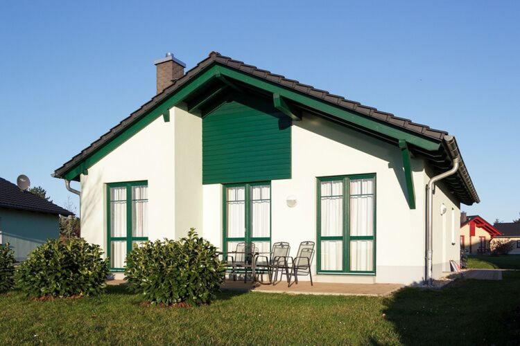 Casa blanca con techo verde, mesa y sillas en Holiday home in Markkleeberg near a lake en Markkleeberg