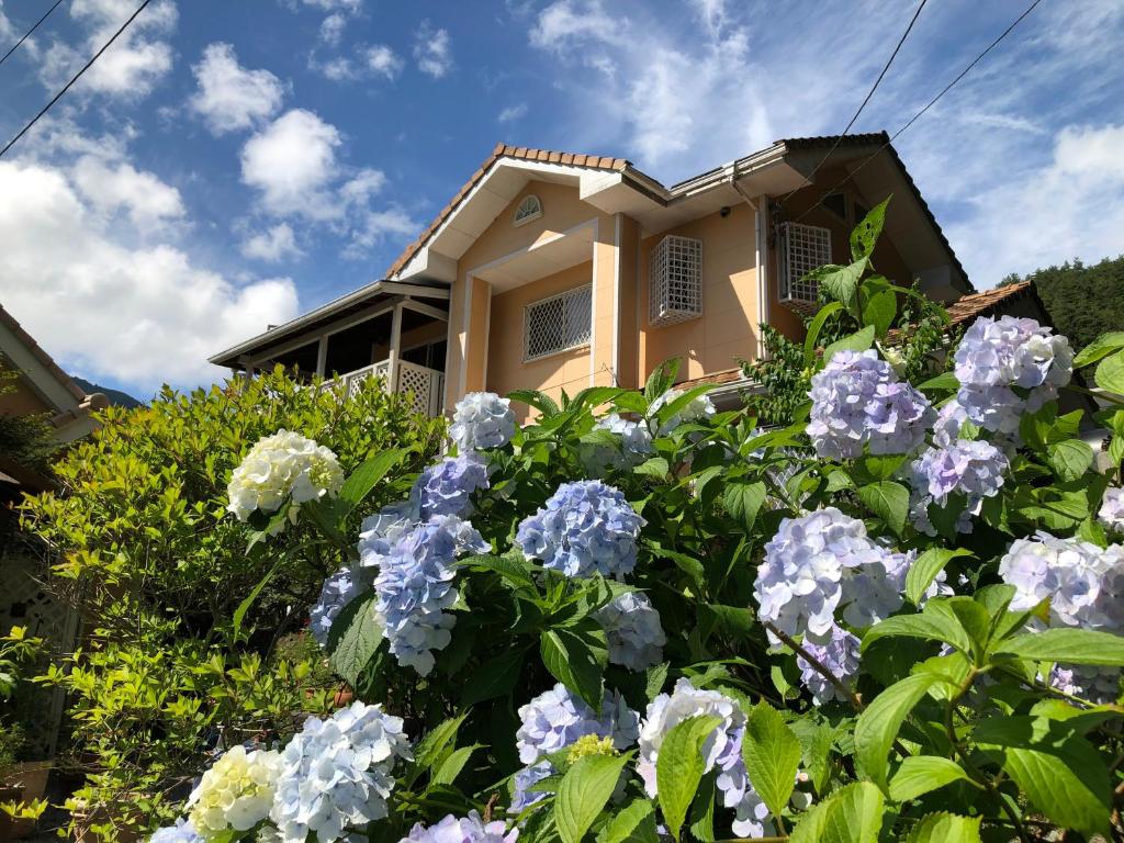 a house with blue and white flowers in front of it at Villa Relax in Fujikawaguchiko