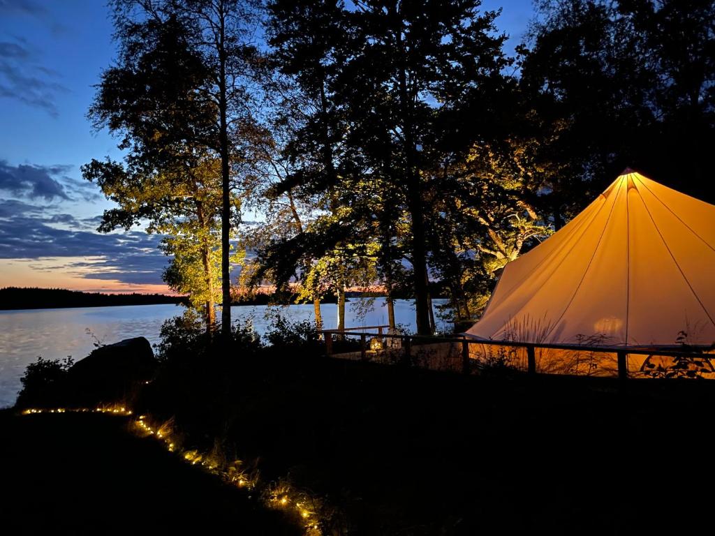 a tent on the shore of a lake at night at Urshult Glamping in Urshult