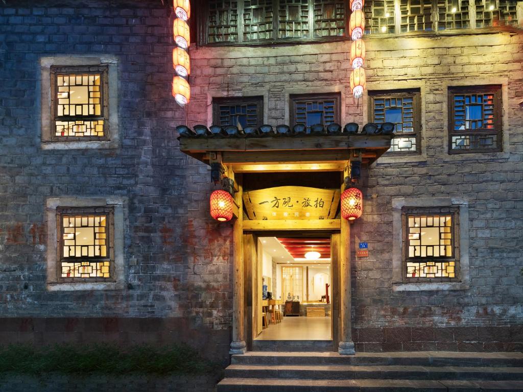 un ingresso a un edificio con un cartello sopra di 一方砚·旅拍体验民宿 a Fenghuang