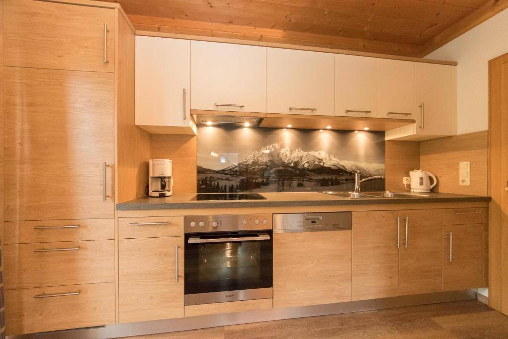 a kitchen with wooden cabinets and an oven at Gästehaus Müllauer in Leogang