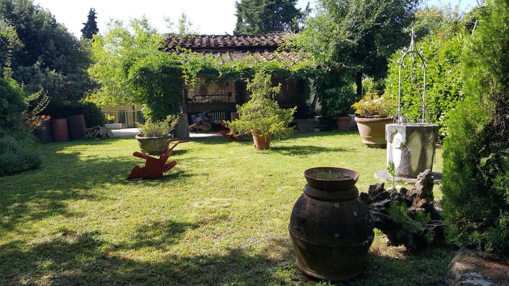 un jardín con un cenador y un jarrón en la hierba en Agriturismo Podere I' Caldino, en Troghi