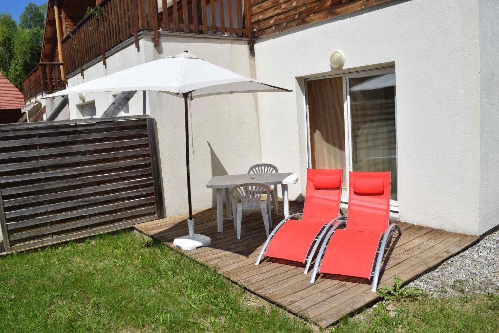 un patio con mesa, sillas y sombrilla en T3 coquet et lumineux aux pieds des pistes en Ancelle