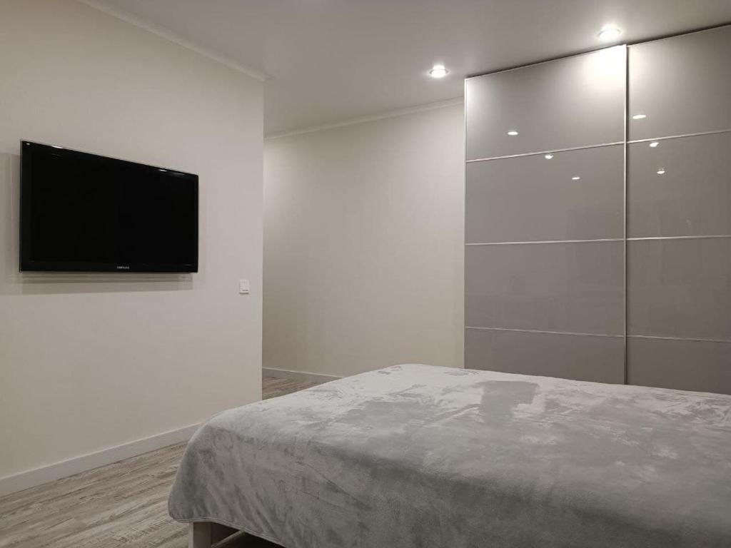 een witte kamer met een bed en een flatscreen-tv bij Апартаменты на первой линии до моря 50 метров in Novorossiejsk