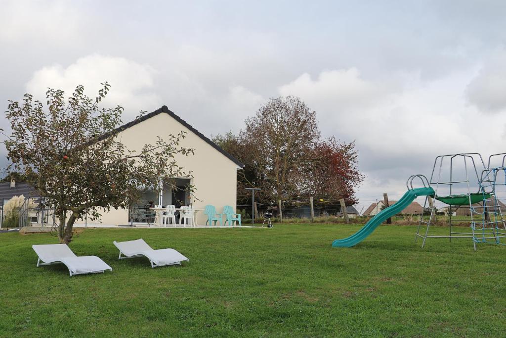 un parque infantil con un tobogán y 2 sillas en un patio en gîte la bêcyclette de la baie de Somme, en Mons-Boubert