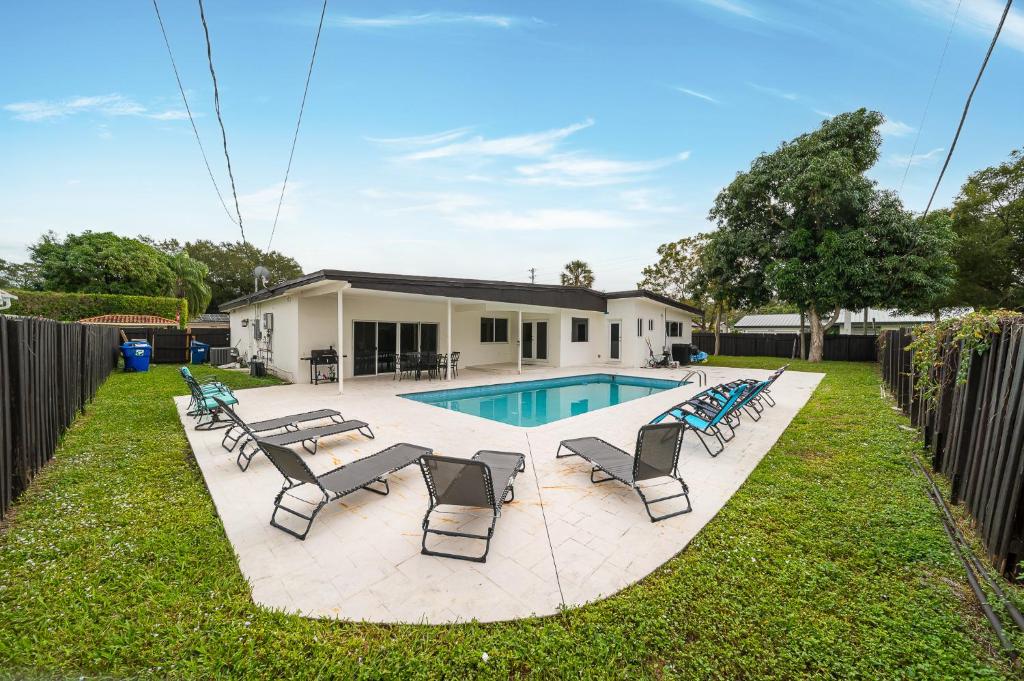 einen Hinterhof mit Pool und Stühlen und ein Haus in der Unterkunft Pool Villa in Miami