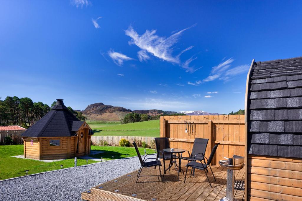 a deck with chairs and a small wooden house at Laggan Luxury Highland Glamping in Newtonmore