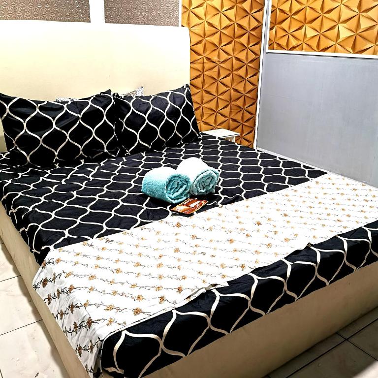 1 cama con edredón blanco y negro y 2 toallas en Cabantuan City PNY TRANSIENT INN 5 en Cabanatuan