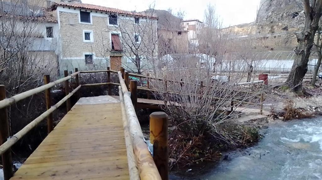 uma ponte de madeira sobre um rio com neve no chão em Molino Elidio em Pontones
