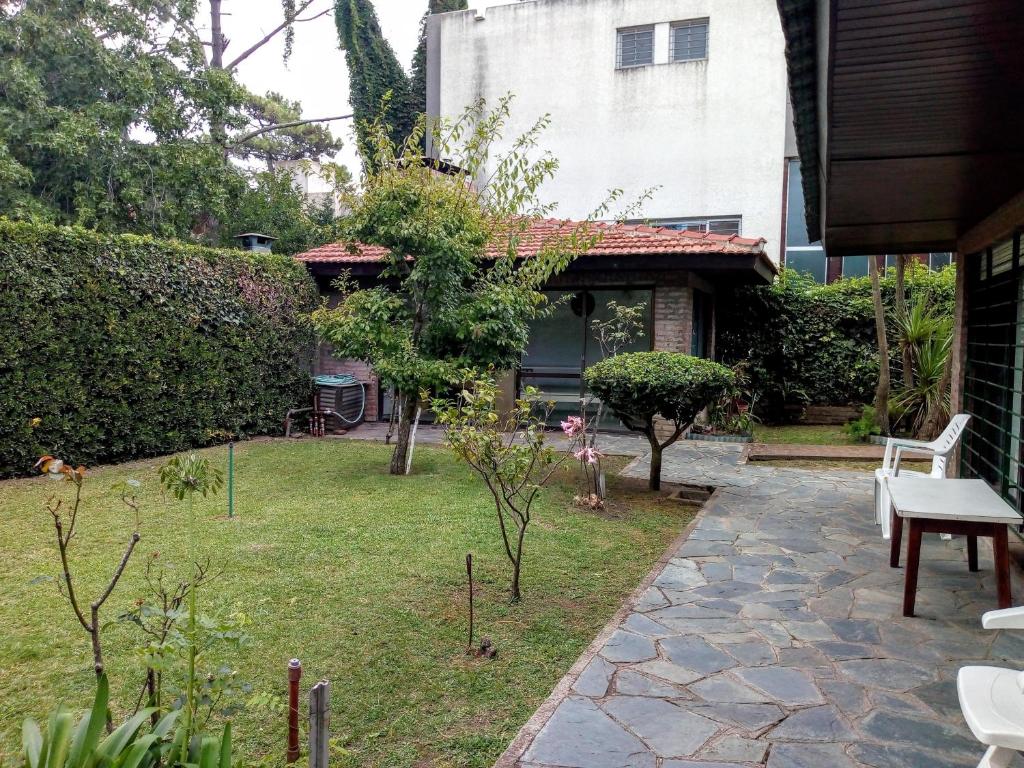 un jardín con mesa y sillas en un patio en Tejas Verdes Alojamiento Familiar en Villa Gesell