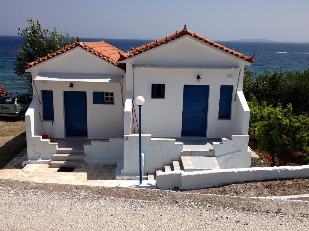 een wit huis met blauwe deuren voor de oceaan bij George Paradise in Nees Kidonies