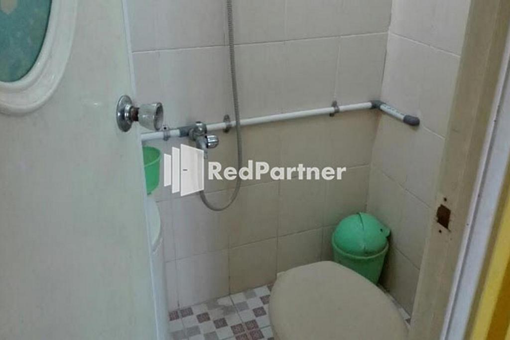 baño con aseo y cubo de basura verde en Bromo Indah Lestari Homestay Mitra RedDoorz, en Pasuruan