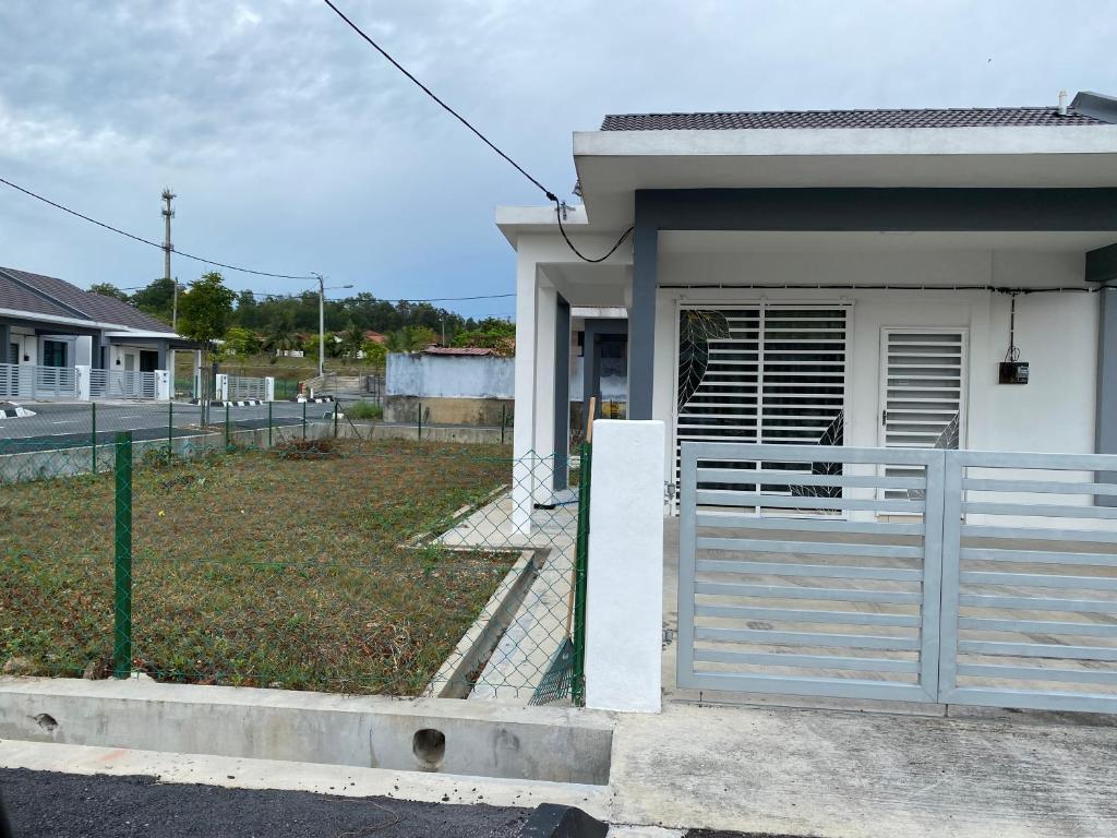 ein weißes Haus mit einem Tor davor in der Unterkunft An-Nur Homestay in Sungai Petani