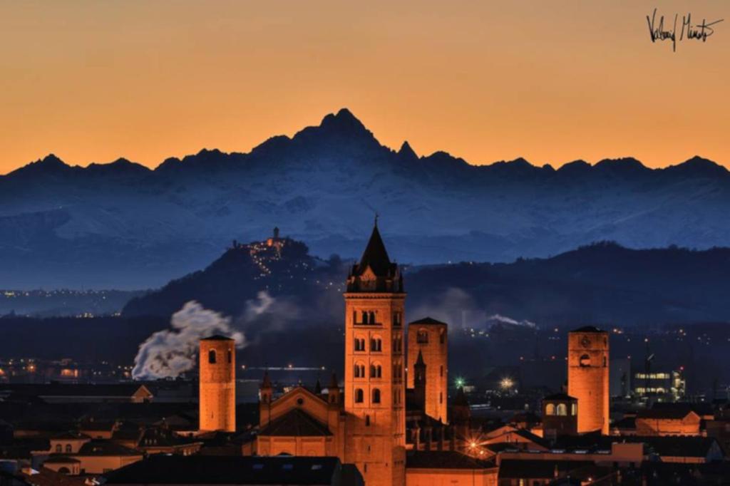 een gebouw met een klokkentoren met bergen op de achtergrond bij Alba la capitale delle Langhe in Alba