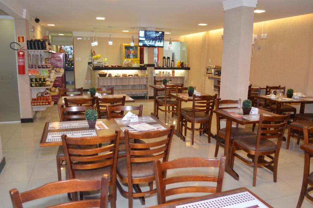 un restaurante lleno de mesas y sillas de madera en Hotel Grande Minas en Vespasiano
