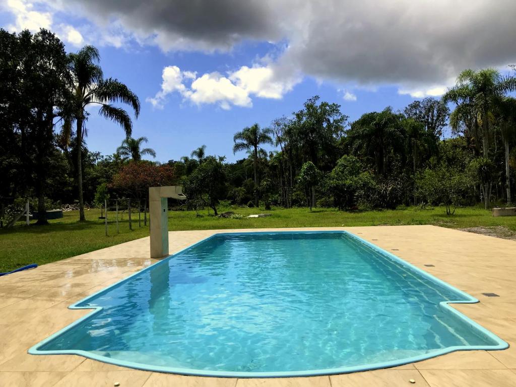 a swimming pool in a park with trees in the background at Casa Chácara Zulin's,-SIMPLICIDADE E AMOR in Pontal do Paraná