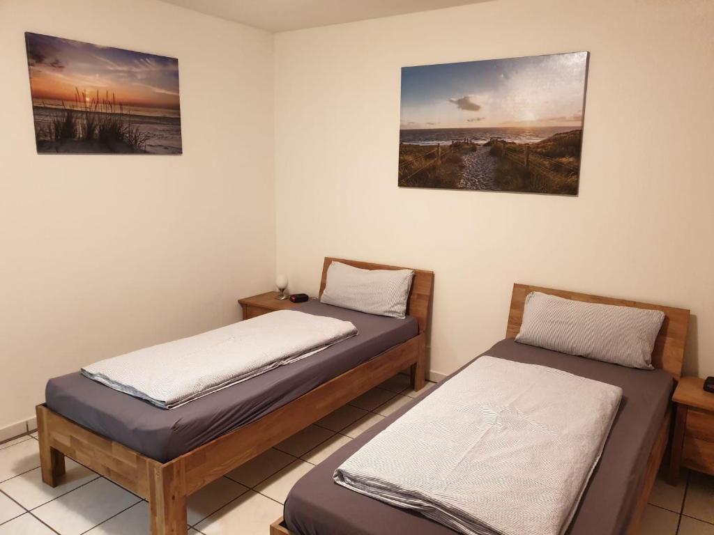 two beds in a room with paintings on the wall at Ferienwohnung Calabria Nr 2 in Mülheim an der Ruhr