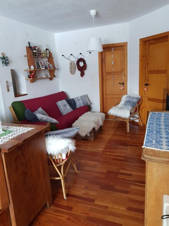 un soggiorno con divano rosso e pavimenti in legno di Trento- Monte Bondone Appartamento tipico di montagna a Norge