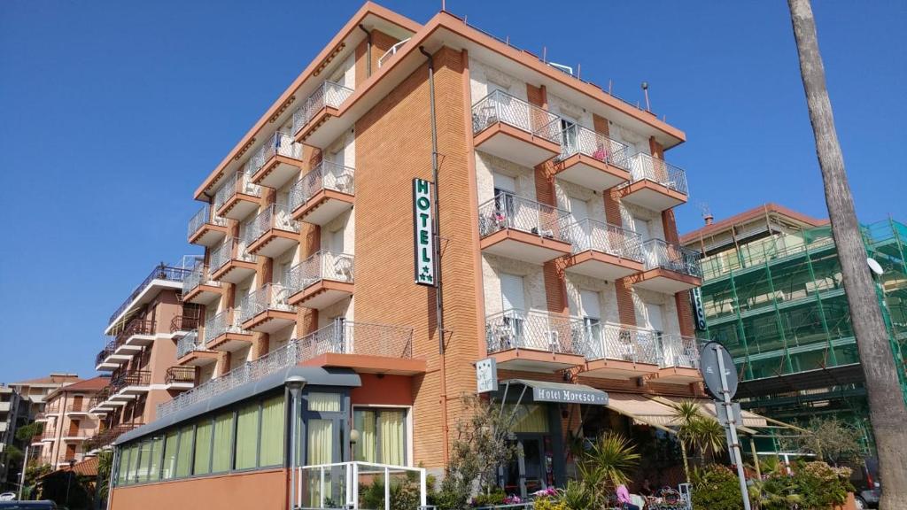 Un grand bâtiment orange avec un panneau. dans l'établissement Hotel Moresco, à Marina dʼAndora