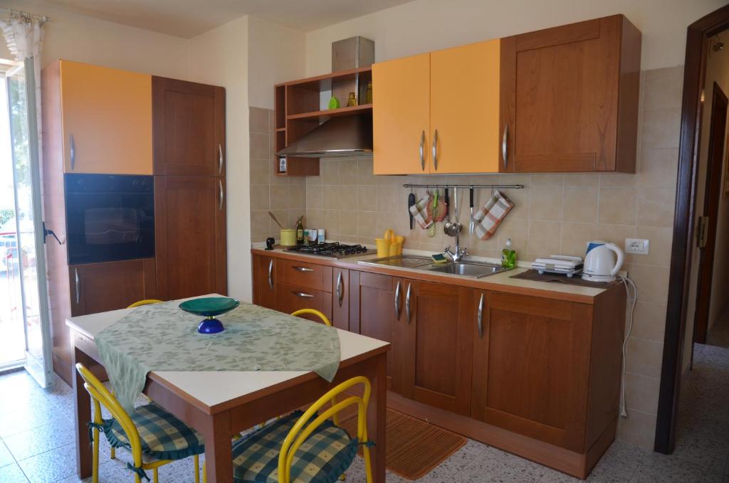 a kitchen with wooden cabinets and a table with chairs at Casa Susanna in Fondachello