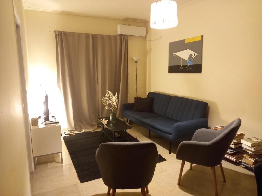 uma sala de estar com um sofá azul e cadeiras em Fresh and elegant apartment, 9' from city center em Atenas