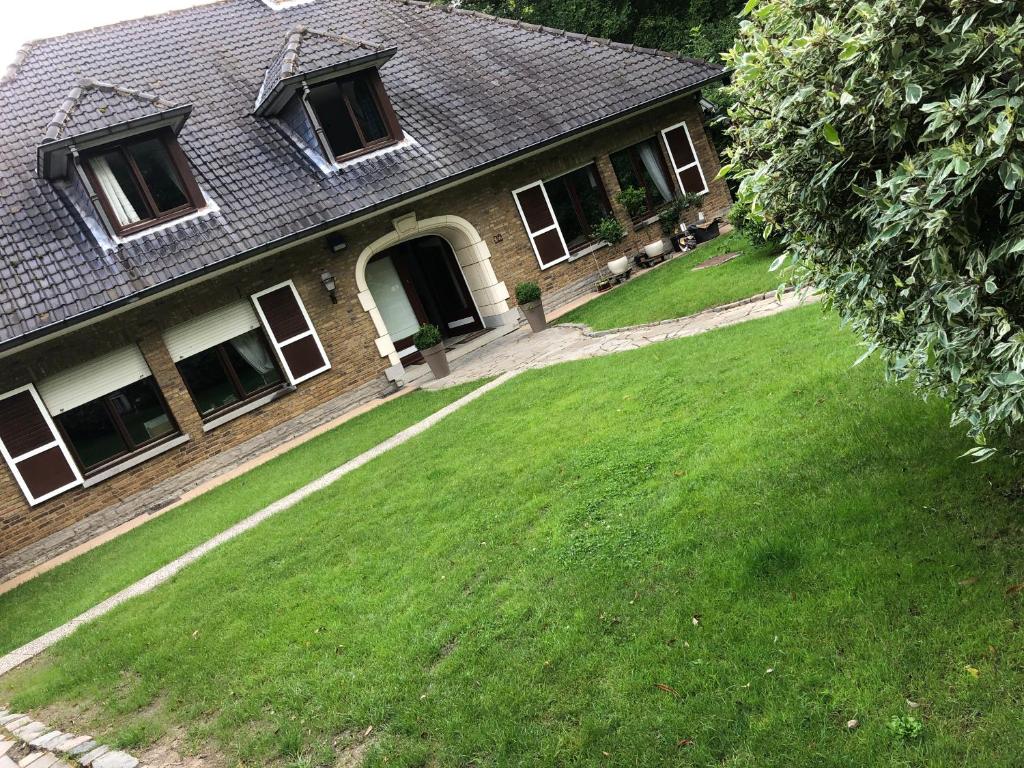 een huis met een groen gazon ervoor bij cosy-rooms-party-villa in Bierges
