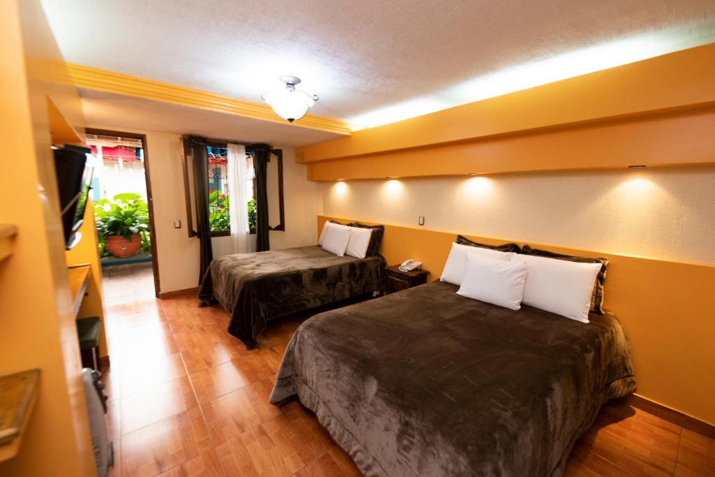 a hotel room with two beds and a flat screen tv at Gran Hotel El Encanto in San Cristóbal de Las Casas
