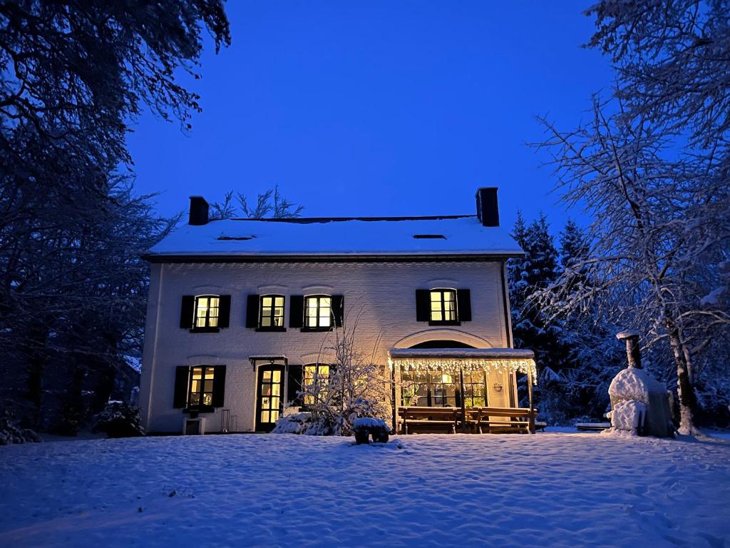 a large house with lights on in the snow at Forester in Malmedy