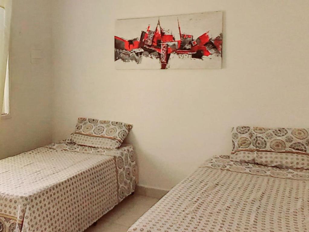 Casa Petit - Banheiro Exclusivo في ناتال: غرفة نوم بسريرين وصورة على الحائط