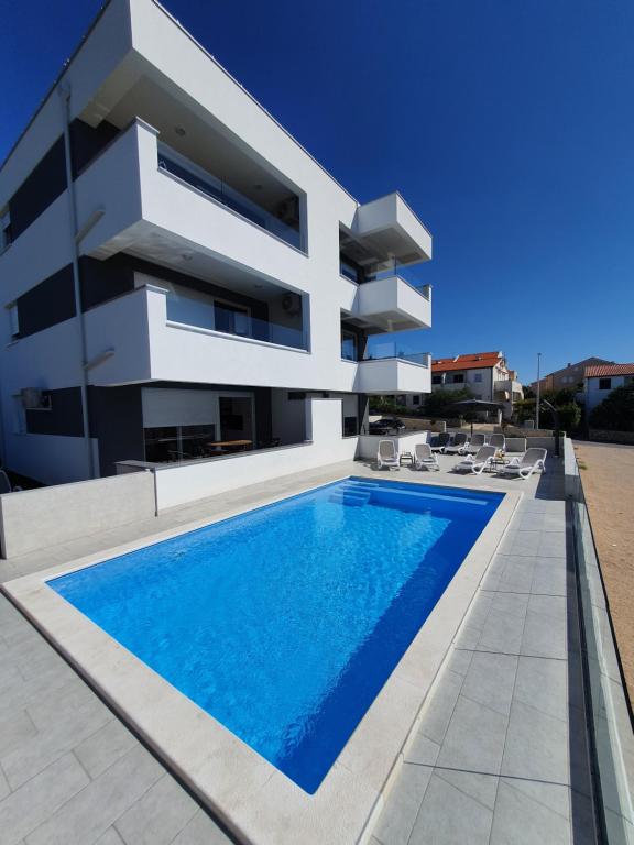 ein großes weißes Haus mit einem Pool in der Unterkunft Aquarius Luxury apartment with pool and sea view in Novalja